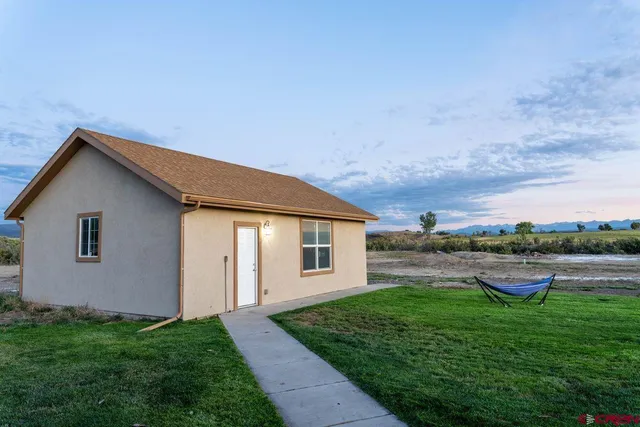 a backyard of a house with table and chairs and wooden fence