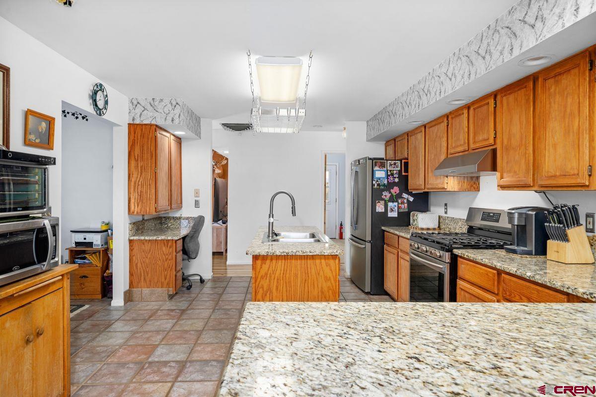 66460 Ogden Road Montrose, CO 81401 - Photo 5 of 40 a kitchen with stainless steel appliances granite countertop a stove top oven a sink dishwasher and cabinets with wooden floor