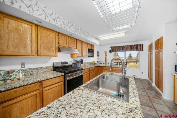 a kitchen with granite countertop a sink window and cabinets