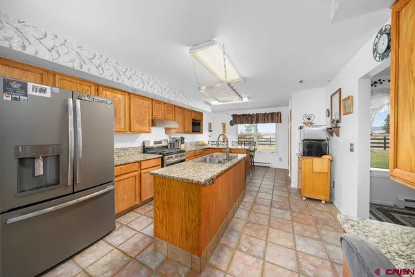 a large kitchen with stainless steel appliances granite countertop a refrigerator and a stove