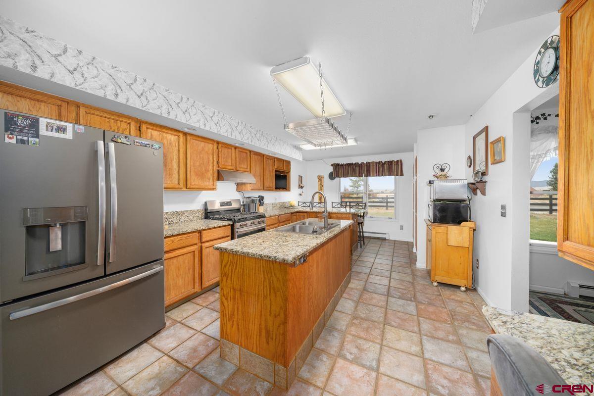 66460 Ogden Road Montrose, CO 81401 - Photo 7 of 40 a large kitchen with stainless steel appliances granite countertop a refrigerator and a stove
