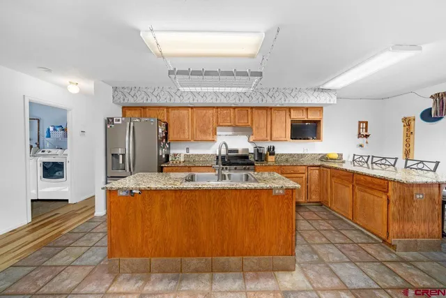a large kitchen with kitchen island a sink a counter top space a large window and stainless steel appliances