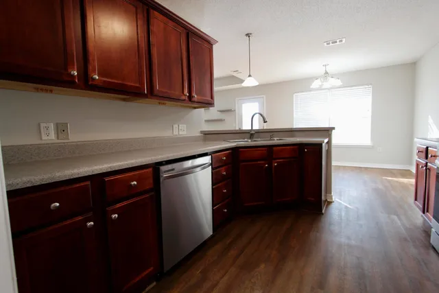 a kitchen with kitchen island granite countertop a sink cabinets and wooden floor