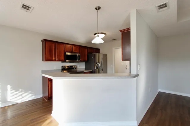 a kitchen with stainless steel appliances granite countertop a sink a stove top oven a refrigerator with wooden floors