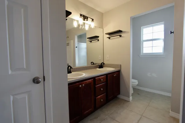 a spacious bathroom with a double vanity sink toilet and a mirror