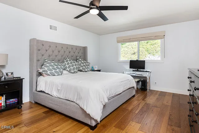 a bedroom with a bed and a flat tv screen on the dresser