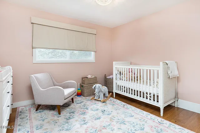 a bedroom with a baby bed a couch and a window