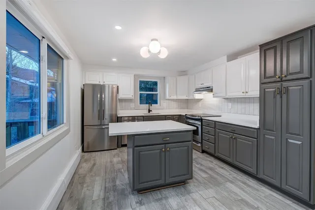 a kitchen with stainless steel appliances granite countertop a refrigerator a sink dishwasher a stove with wooden cabinets and floors