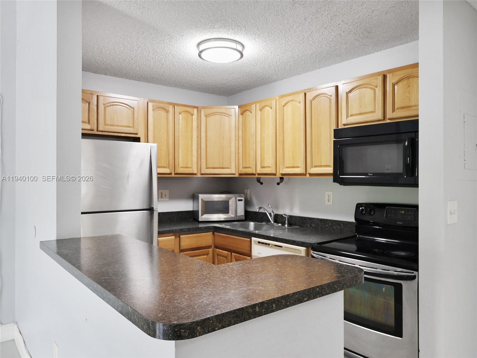 15520 Southwest 80th Street, Unit B301 Miami, FL 33193 - Photo 14 of 26 a kitchen with stainless steel appliances granite countertop a sink a stove and a microwave