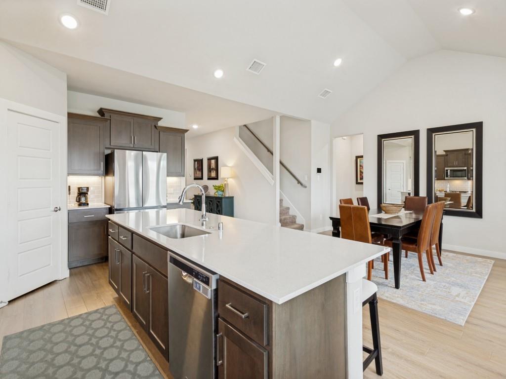 10613 Smiths Bnd Road Fort Worth, TX 76126 - Photo 8 of 29 Open-concept kitchen and dining area featuring a spacious island with an undermount sink, stainless steel appliances, dark wood cabinetry, and light wood-finish flooring