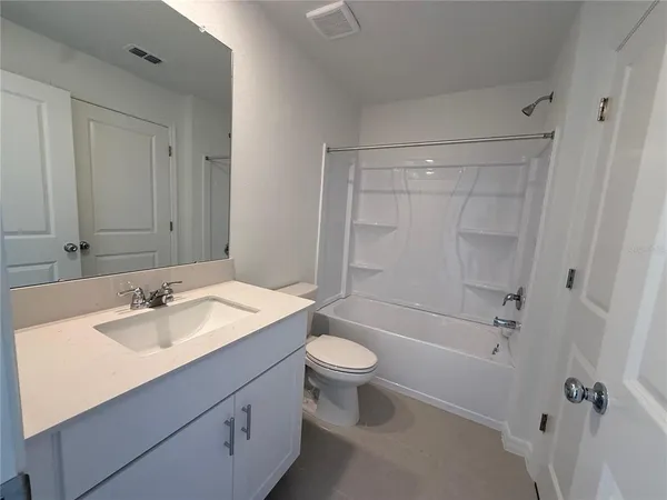 a bathroom with a granite countertop toilet and a sink
