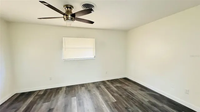 a view of a room with wooden floor and a ceiling fan