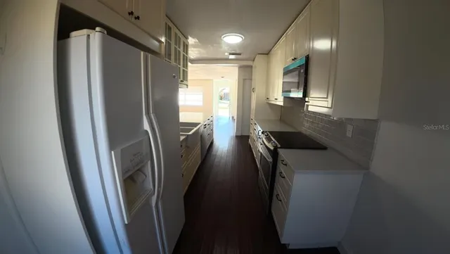 a view of a refrigerator in kitchen and an empty room