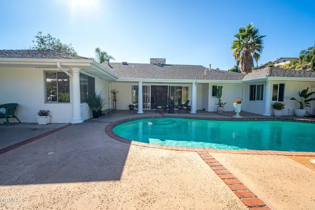 a view of a dining room with furniture a chandelier and large windows