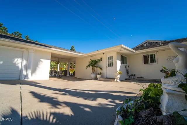 a view of a house with a yard and potted plants