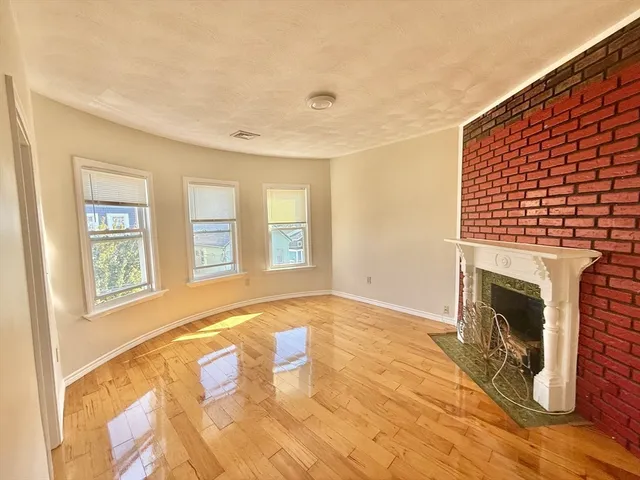 a view of an empty room with window and fire place