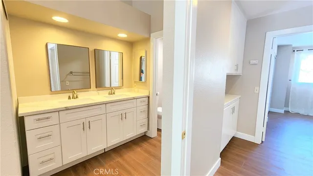 a bathroom with a double vanity sink and mirror with wooden floor