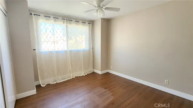 an empty room with wooden floor closet and windows