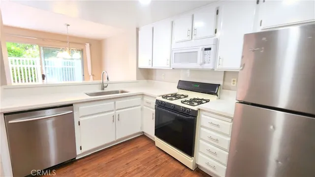 a kitchen with granite countertop a refrigerator stove and sink with wooden floor
