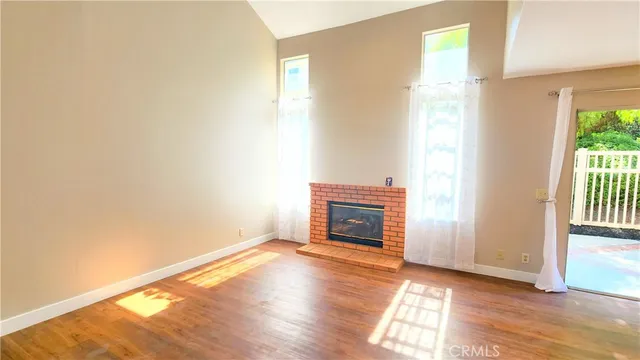 a view of empty room with wooden floor and fireplace