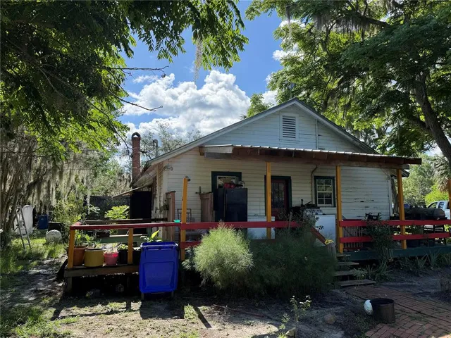 a front view of house with yard outdoor seating and covered with trees