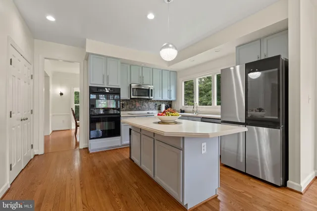 a kitchen with kitchen island granite countertop a sink cabinets and wooden floor
