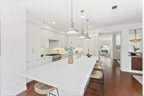 a view of a kitchen with kitchen island a stove a chandelier a sink and wooden floor