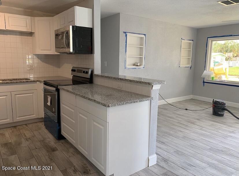 2806 Tropic Road Melbourne, FL 32935 - Photo 16 of 17 a kitchen with stainless steel appliances granite countertop a sink stove and microwave