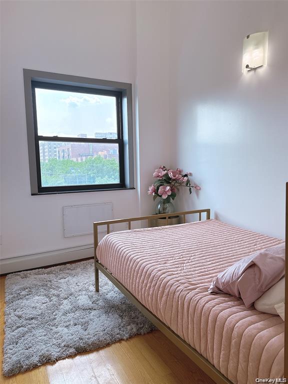 31-47 137th Street, Unit 4C Queens, NY 11354 - Photo 8 of 11 Bedroom featuring wood finished floors, radiator, and a baseboard radiator