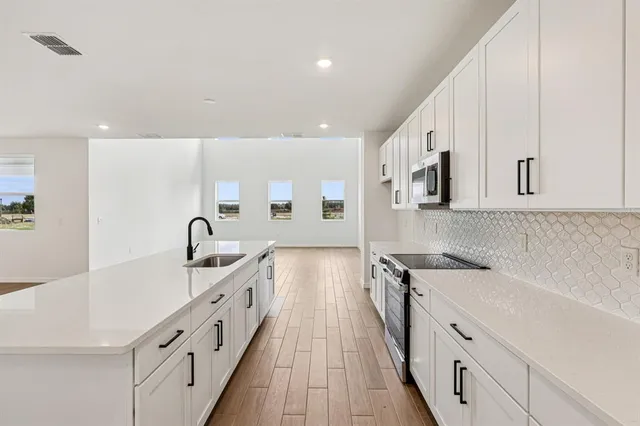 a open kitchen with a sink and wooden floor