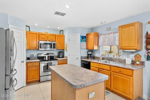 a kitchen with stainless steel appliances a refrigerator a stove a dining table and chairs