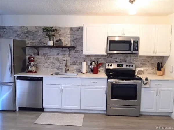 a kitchen with stainless steel appliances white cabinets and a stove top oven
