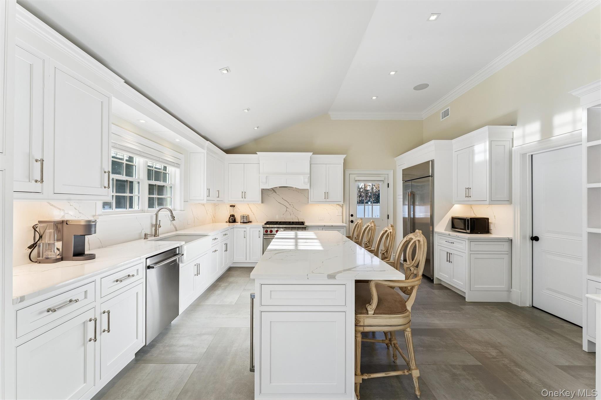 275 Mill Road Westhampton Beach, NY 11978 - Photo 7 of 23 Kitchen featuring a kitchen breakfast bar, lofted ceiling, white cabinets, light quartz counters, and a kitchen island.