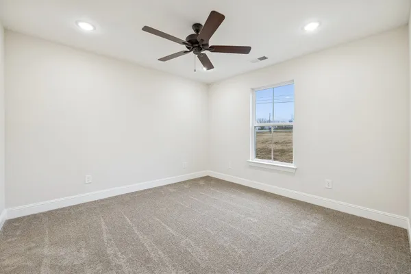 an empty room with ceiling fan and window