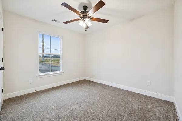 an empty room with a window and a fan