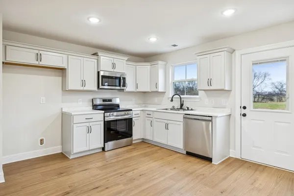 a kitchen with granite countertop white cabinets and stainless steel appliances