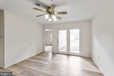 an empty room with wooden floor fan and windows