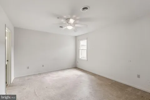 an empty room with a window and a fan