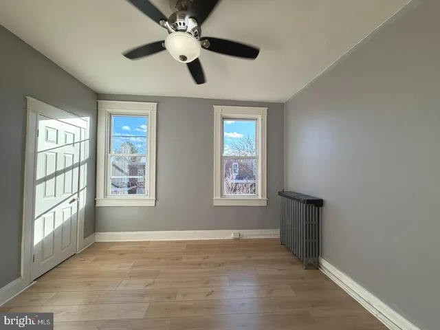 a view of an empty room with a window and wooden floor