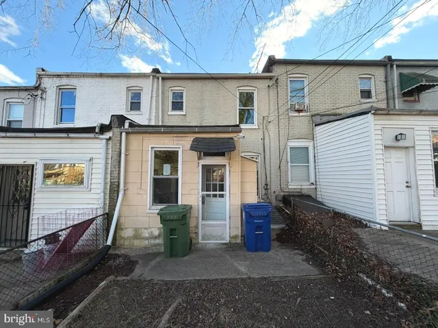 a front view of a house with barbeque and wooden fence