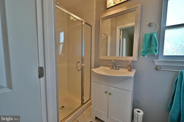 a bathroom with a granite countertop sink a mirror and a shower