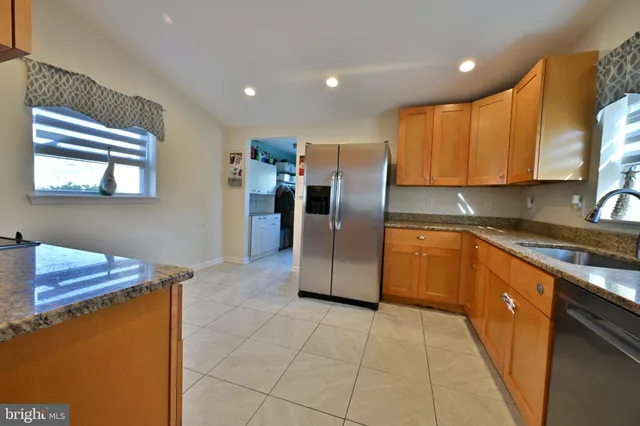 a kitchen with stainless steel appliances granite countertop a refrigerator a sink a stove top oven and a counter space