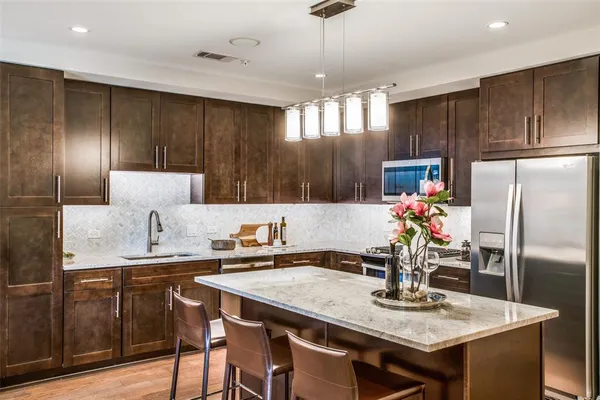 a kitchen with granite countertop a table chairs stove and refrigerator