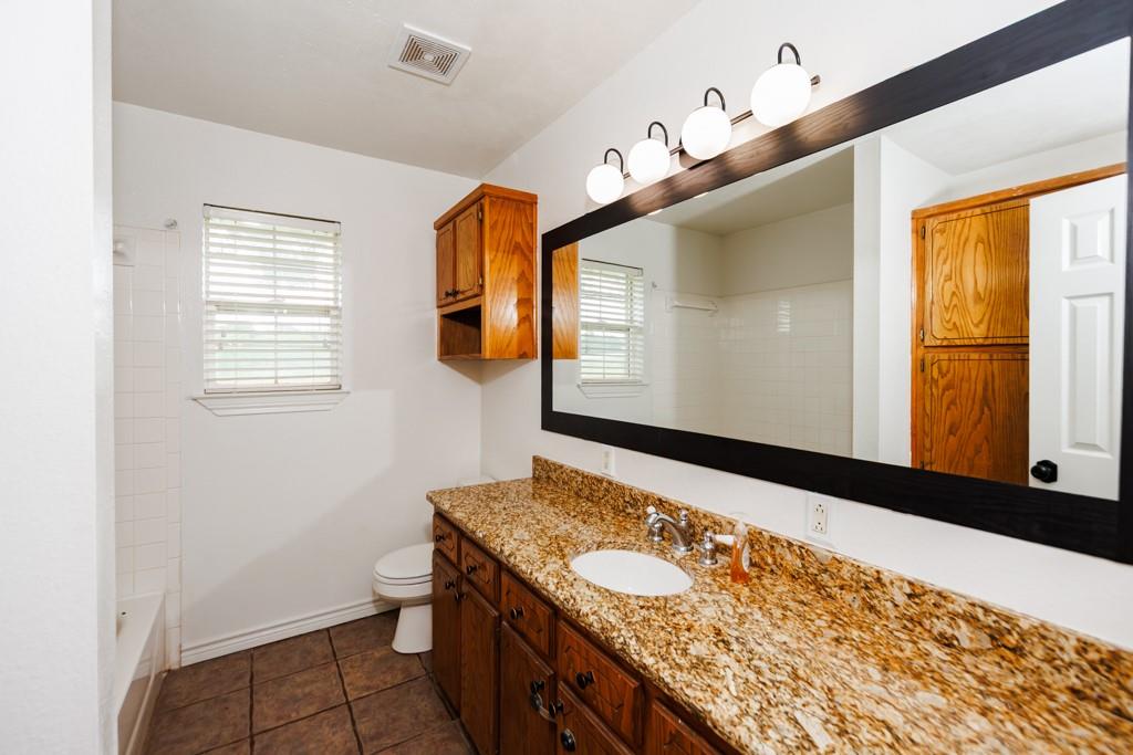 4316 Leona Road Bowie, TX 76230 - Photo 20 of 37 a bathroom with a granite countertop sink and a large mirror