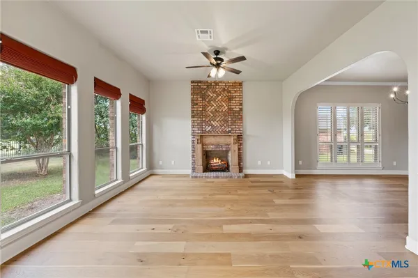 a view of an empty room with a window and wooden floor