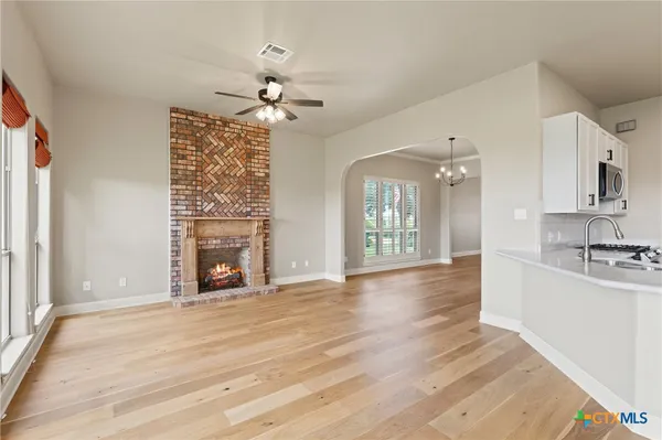 a view of an empty room with a kitchen and a fireplace