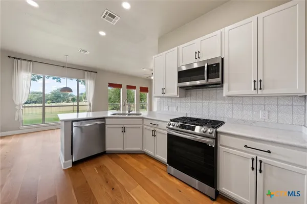 a kitchen with granite countertop cabinets stainless steel appliances and wooden floor