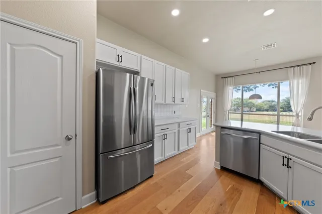a kitchen with stainless steel appliances a refrigerator sink and cabinets