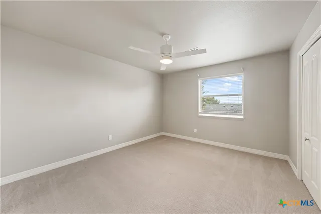 an empty room with windows and ceiling fan