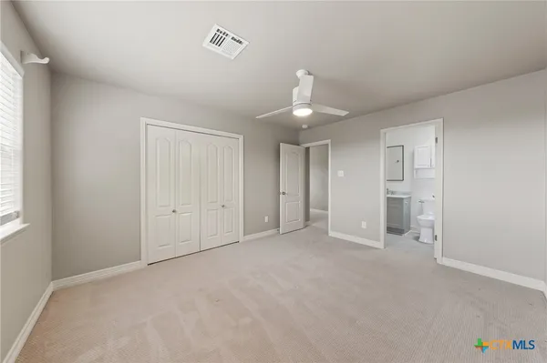 a view of an empty room with window and chandelier fan